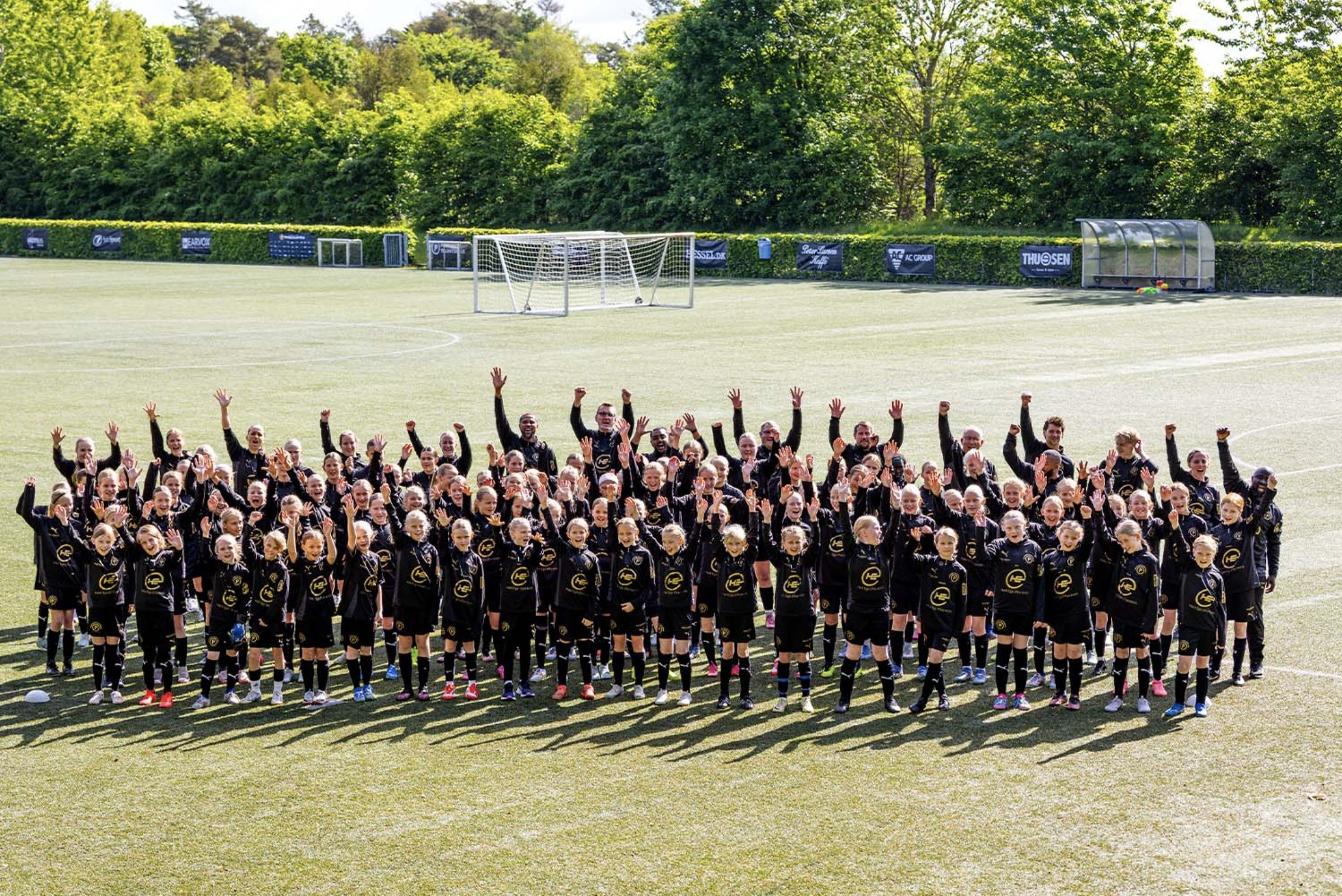 Alle spillere og trænere fra pigetalentskolen jubler på banen